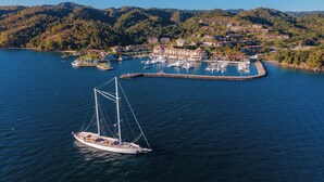 A marina with a sailboat, surrounded by houses and hills. -  Bannister Hotel &  Yacht Club (Samaná)