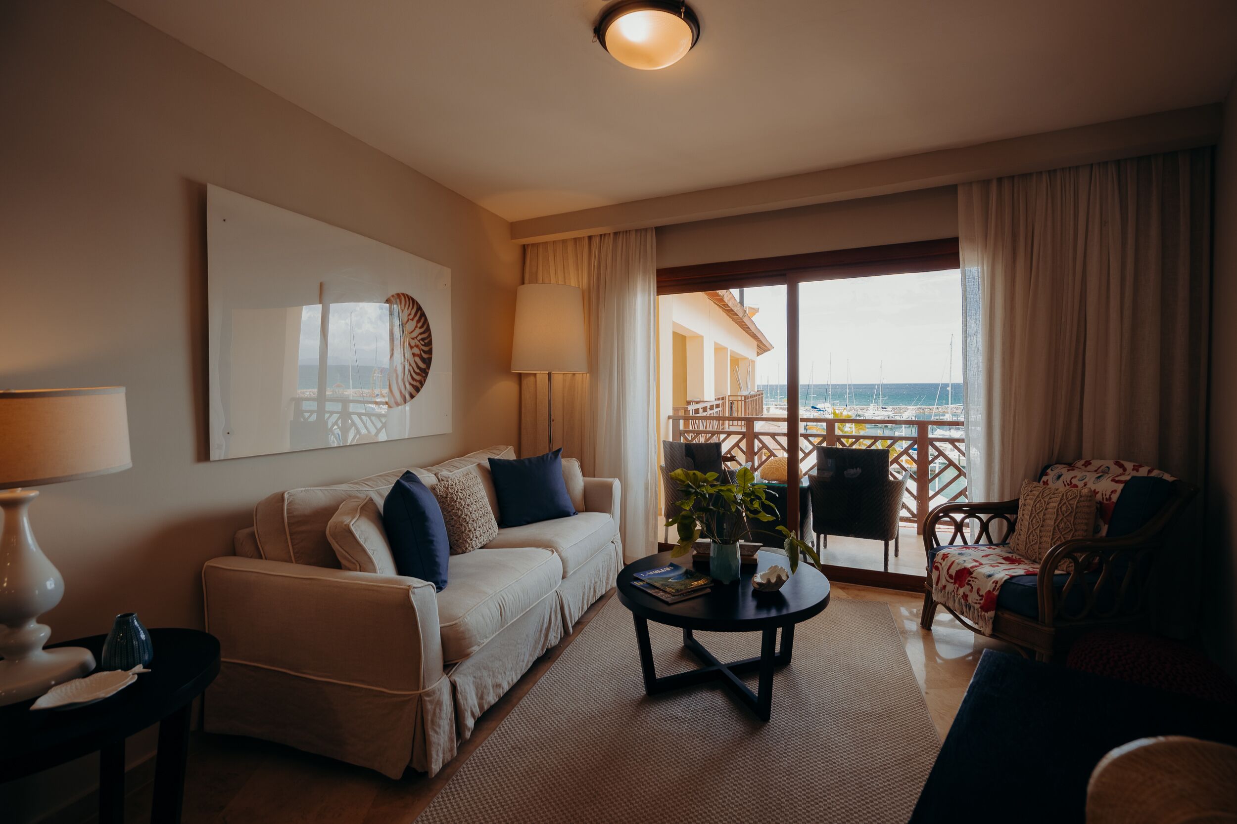 Et hotelværelse med balkon, sofa, sofabord og stol.