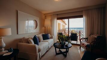 Et hotelværelse med balkon, sofa, sofabord og stol.