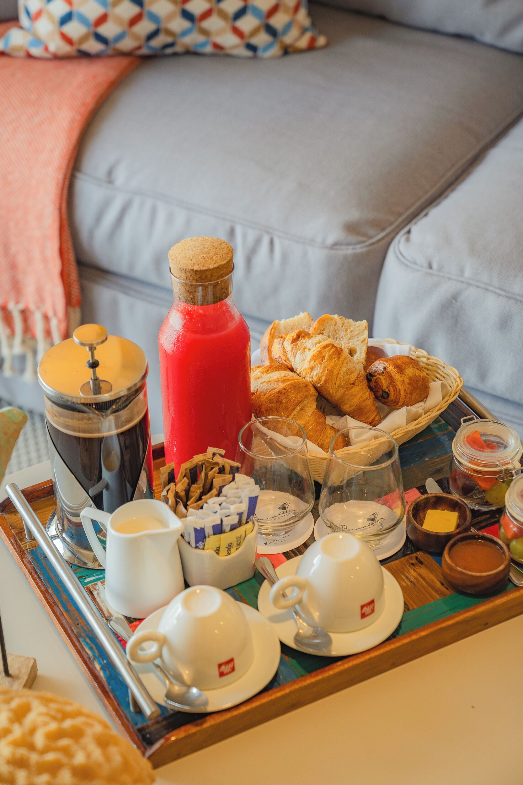 Een ontbijtplateau met croissants, jam en koffie op een houten dienblad.