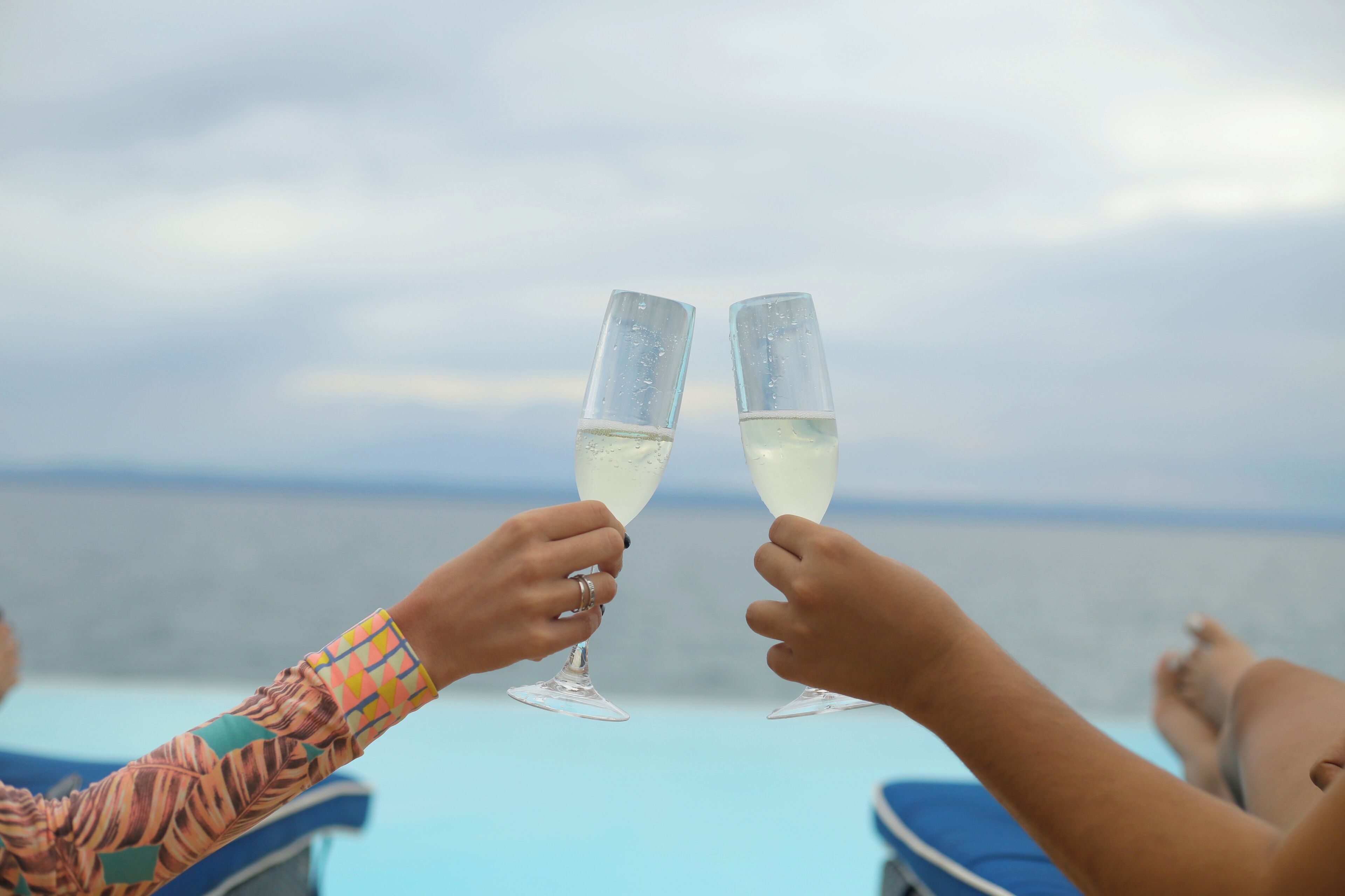 Two people toasting with champagne glasses on a boat with a view of the sea.