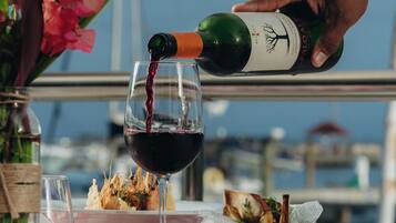 A dining table with a checkered tablecloth, a glass of red wine, a bottle of wine, and a plate with food.