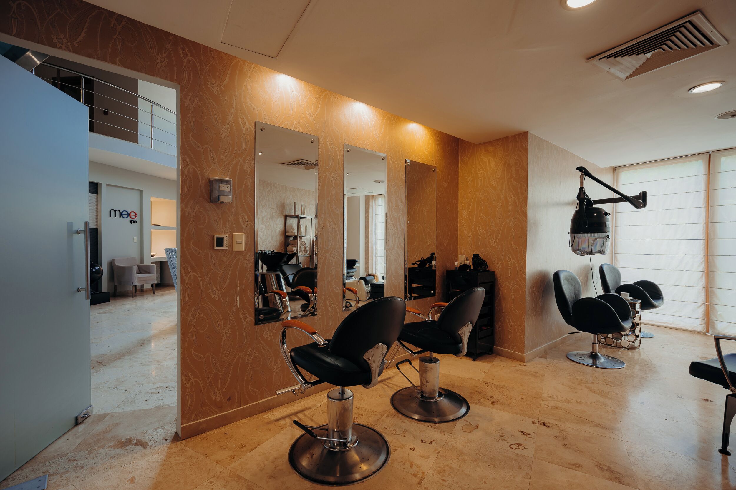 Un salon moderne avec deux fauteuils noirs, un grand miroir et un lampadaire fixé au plafond.