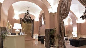 Un vestíbulo amplio con mostrador de recepción, zona de estar y una escalera que conduce a un piso superior.