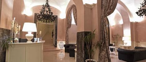 A spacious lobby with a reception desk, seating area, and a staircase leading to an upper floor.