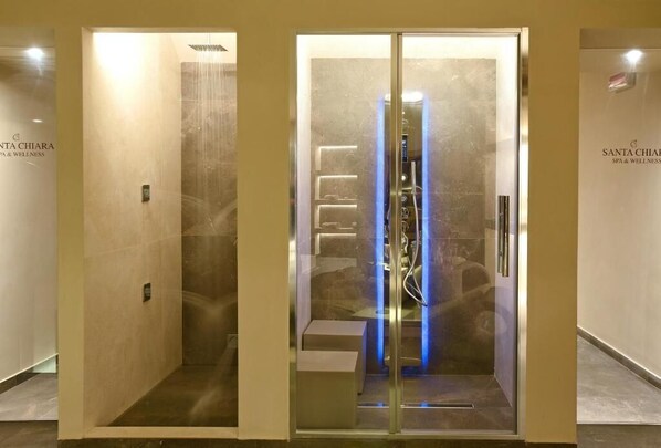 A spa room with a glass door, a shower area, and a bench.