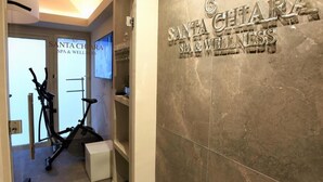 Un pasillo con una bicicleta estática y un cartel en la pared que dice "SANTA CHIARA SPA & WELLNESS".