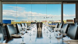 A conference room with a view of a sports field, tables with chairs, and a large window. - Mantra Melbourne Melton (Cobblebank)