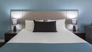 Una cama bien tendida con sábanas blancas, un cabecero oscuro y dos lámparas de noche.