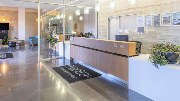 A hotel lobby with a reception desk, seating area, and a staircase leading to another floor. - Mantra Melbourne Melton (Cobblebank)