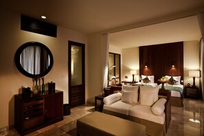 A hotel room with a sofa, a small table, a mirror, a cabinet, and a bed with a nightstand.