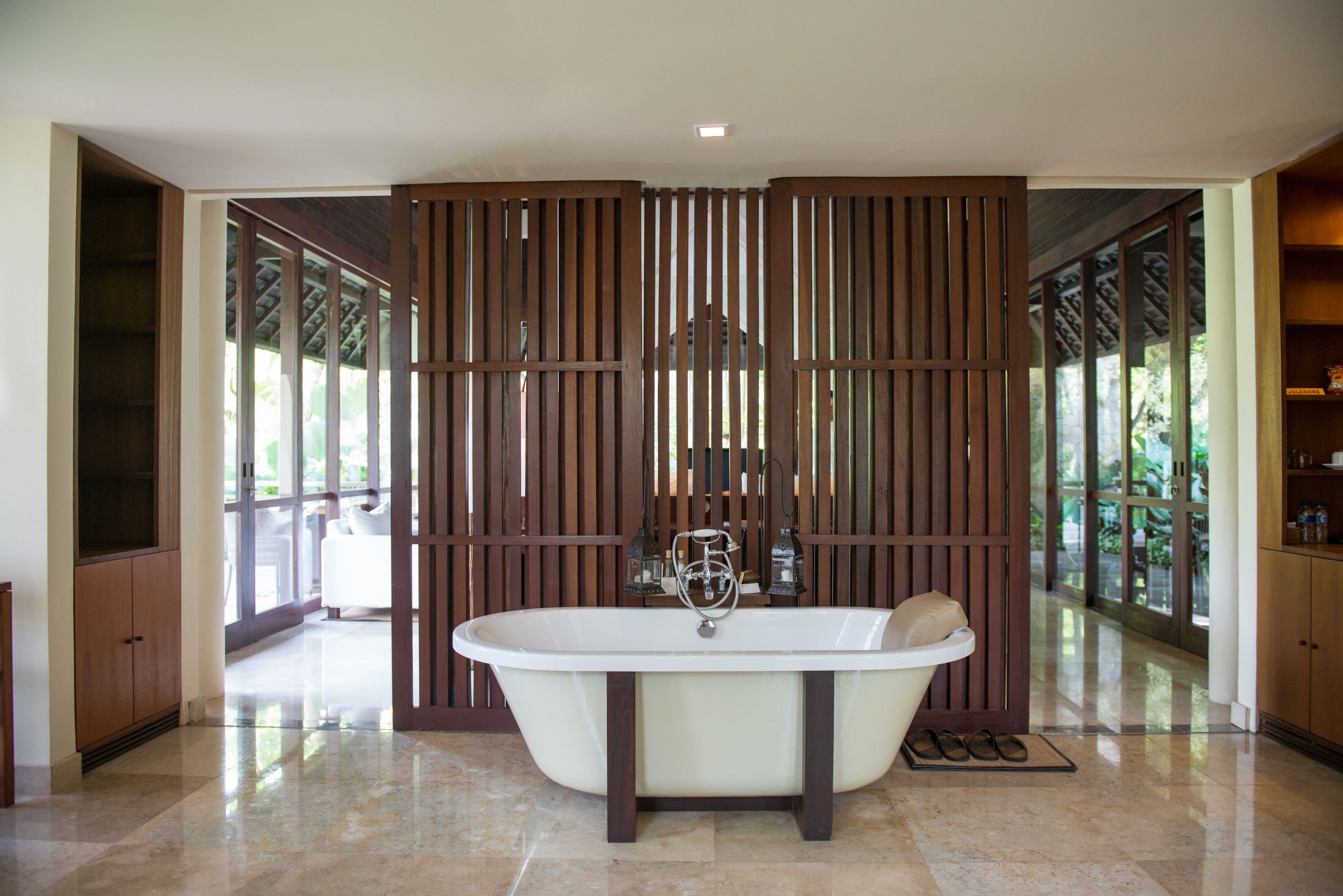 A modern bathroom with a freestanding bathtub, wooden paneling, and large windows.