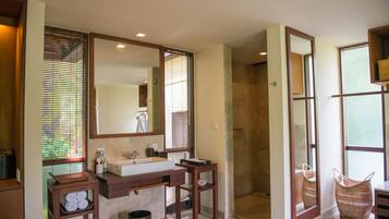 A bathroom with a large mirror, a sink, and a shower.