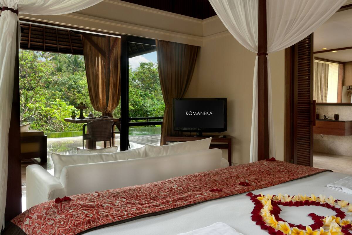 A bedroom with a bed, a TV, and a view of a lush garden.