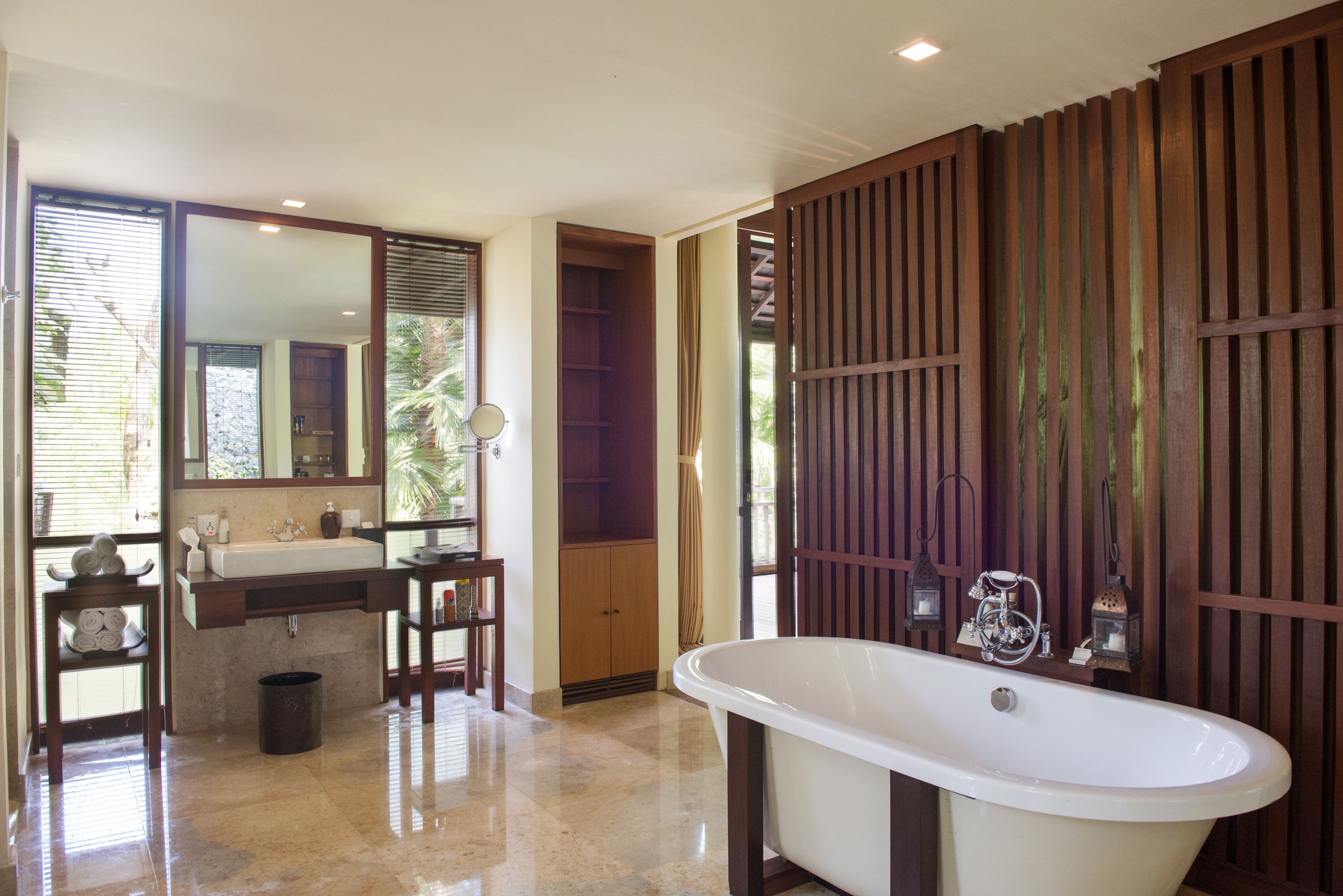 Une salle de bain avec une baignoire sur pieds, un meuble-lavabo avec un miroir et un mur recouvert de panneaux en bois.