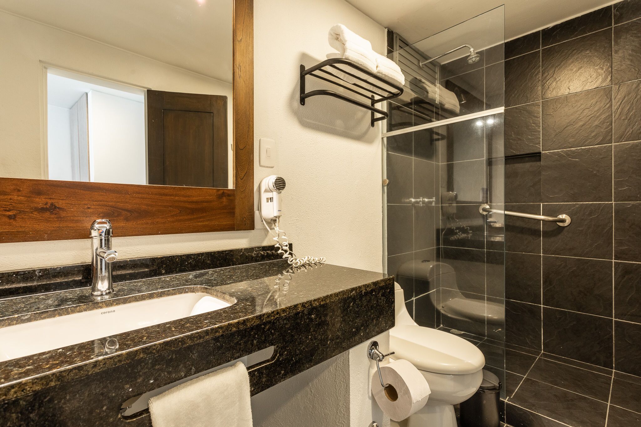 A bathroom with a marble sink, a mirror, a towel rack, a shower, and a toilet.
