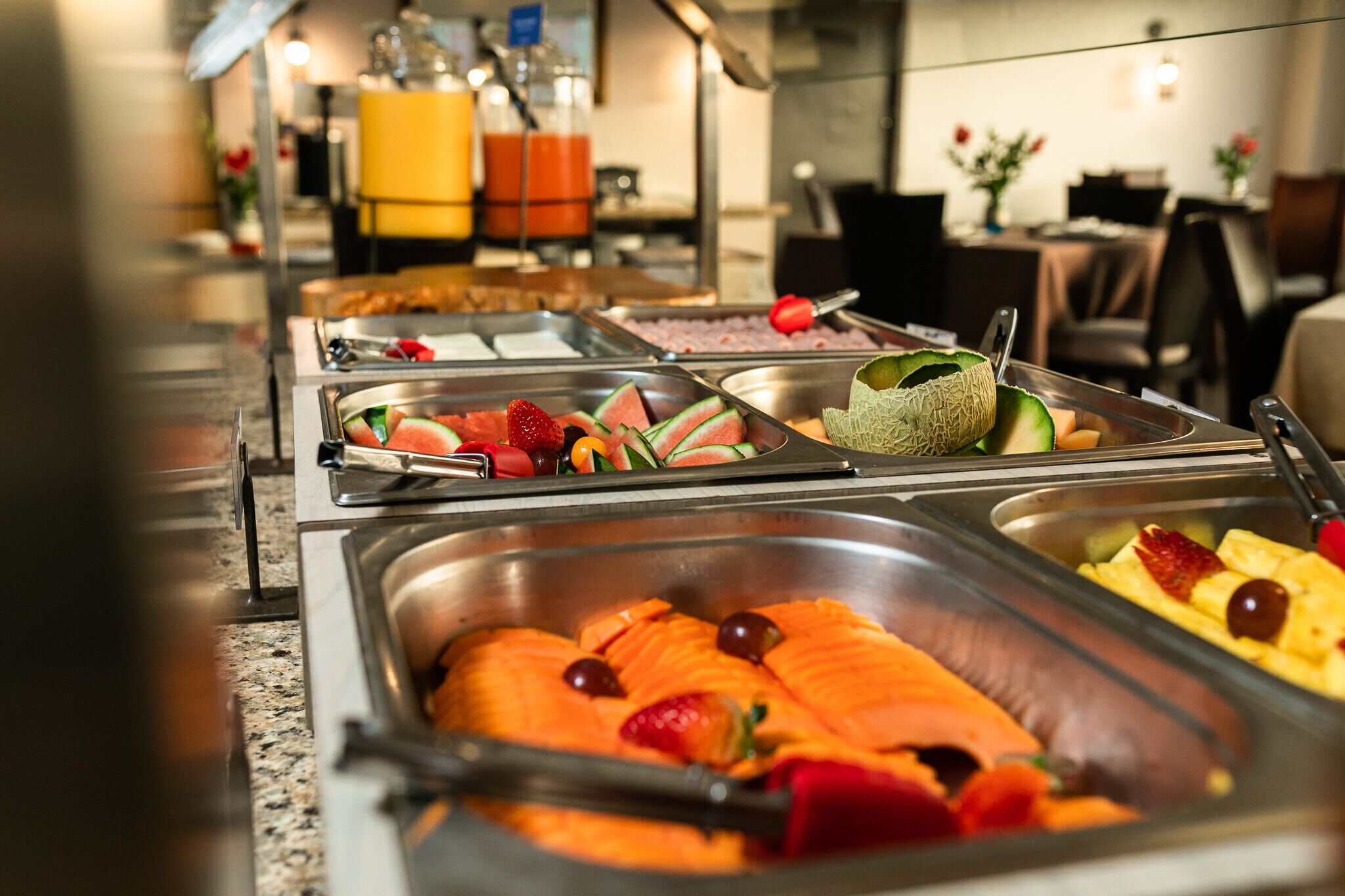 A buffet with various food items including salmon, fruits, and vegetables.