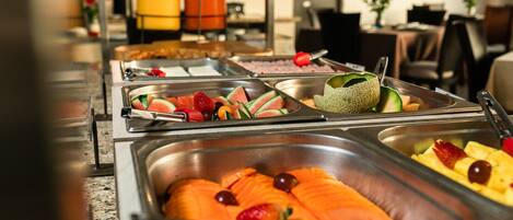 A buffet with various food items including salmon, fruits, and vegetables.