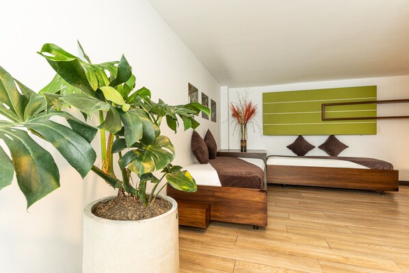 Un dormitorio moderno con una cama de madera, una planta grande en maceta y una obra de arte verde en la pared.
