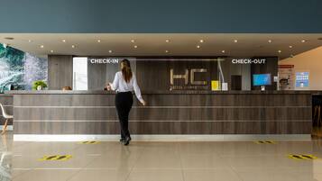 A hotel reception area with a check-in and check-out counter, a digital screen, and a modern design.