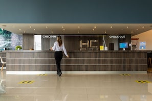 A hotel reception area with a check-in and check-out counter, a digital screen, and a modern design.