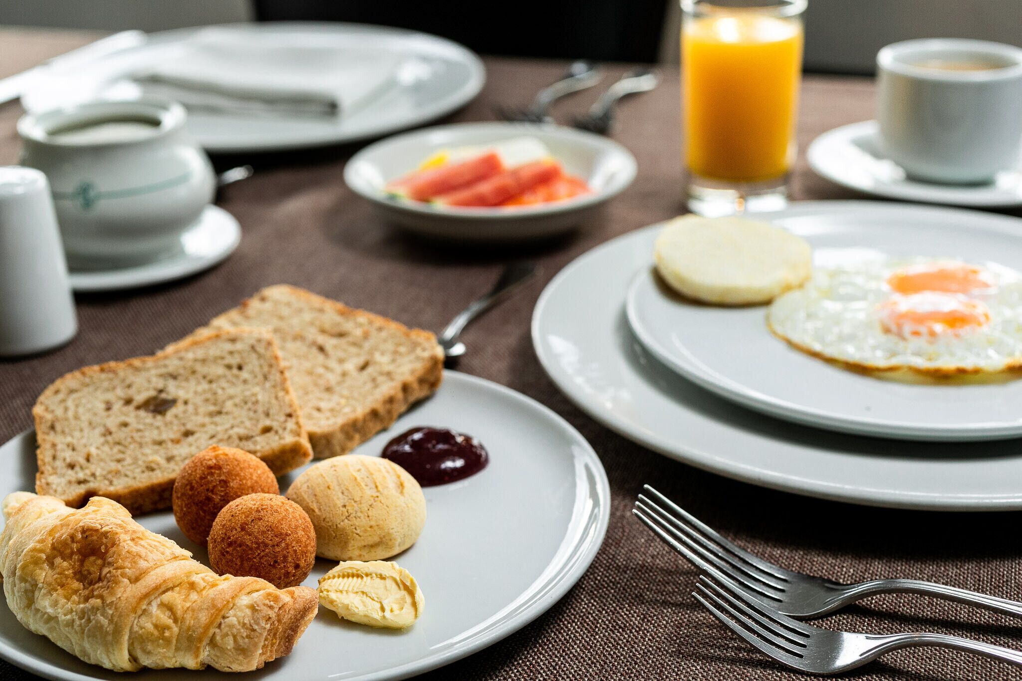A breakfast setting with bread, croissants, and a plate of eggs.