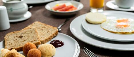 Un desayuno con pan, cruasanes y una fuente de huevos.