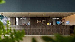 A modern hotel reception area with check-in and check-out counters, a digital screen, and a security camera. - Hotel Carretero (Manizales)