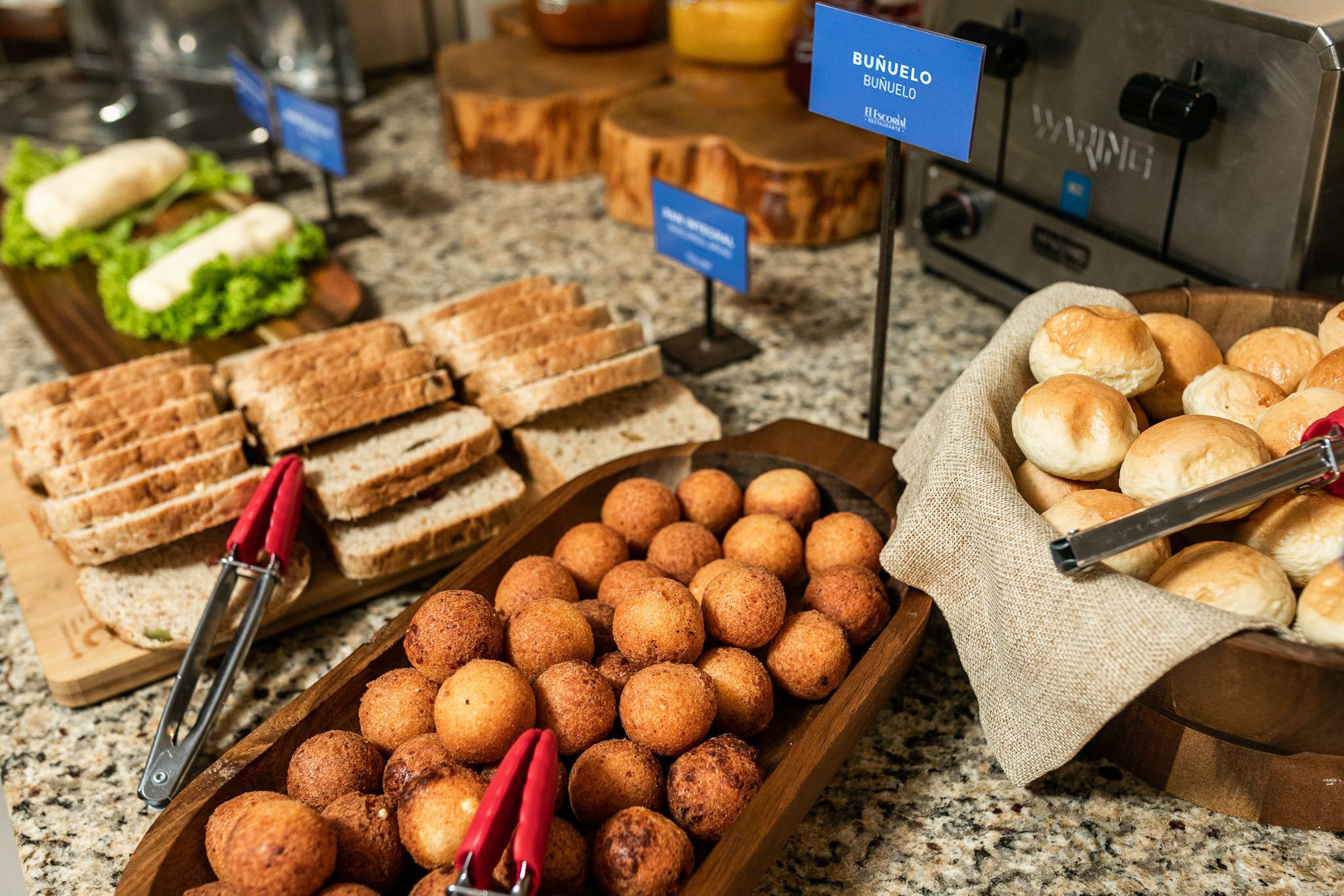 A buffet with various food items including bread, buns, and croquettes.