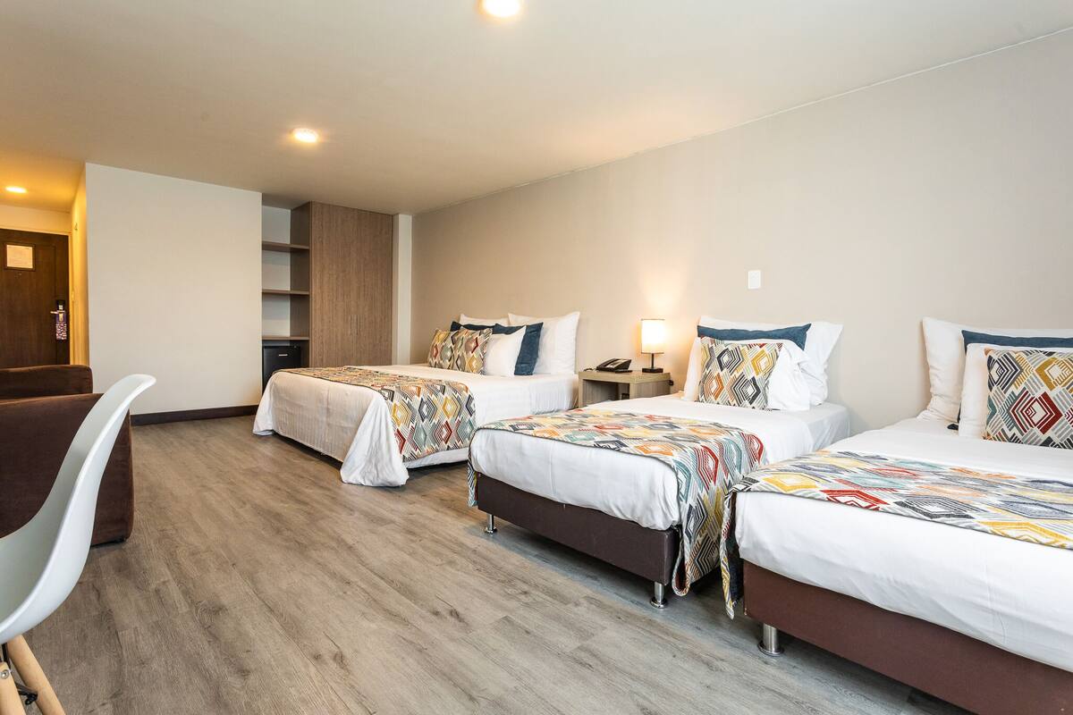 A hotel room with two beds, a desk, and a chair.