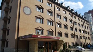 A multi-story hotel with a brick facade, a red awning with the name 'ARION', and a row of potted plants in front. - Hotel Arion (Constanta)