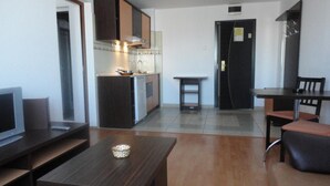 A modern kitchen with dark cabinets, a built-in oven, and a small dining area with a table and chairs. - Hotel Arion (Constanta)