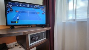 A television on a wooden stand displaying a tennis match, with a control panel below it. - Hotel Arion (Constanta)