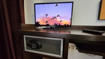 A television on a wooden desk with a remote control, a keypad, and a cable box.