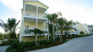 A multi-story hotel with balconies, palm trees, and a clear sky.
