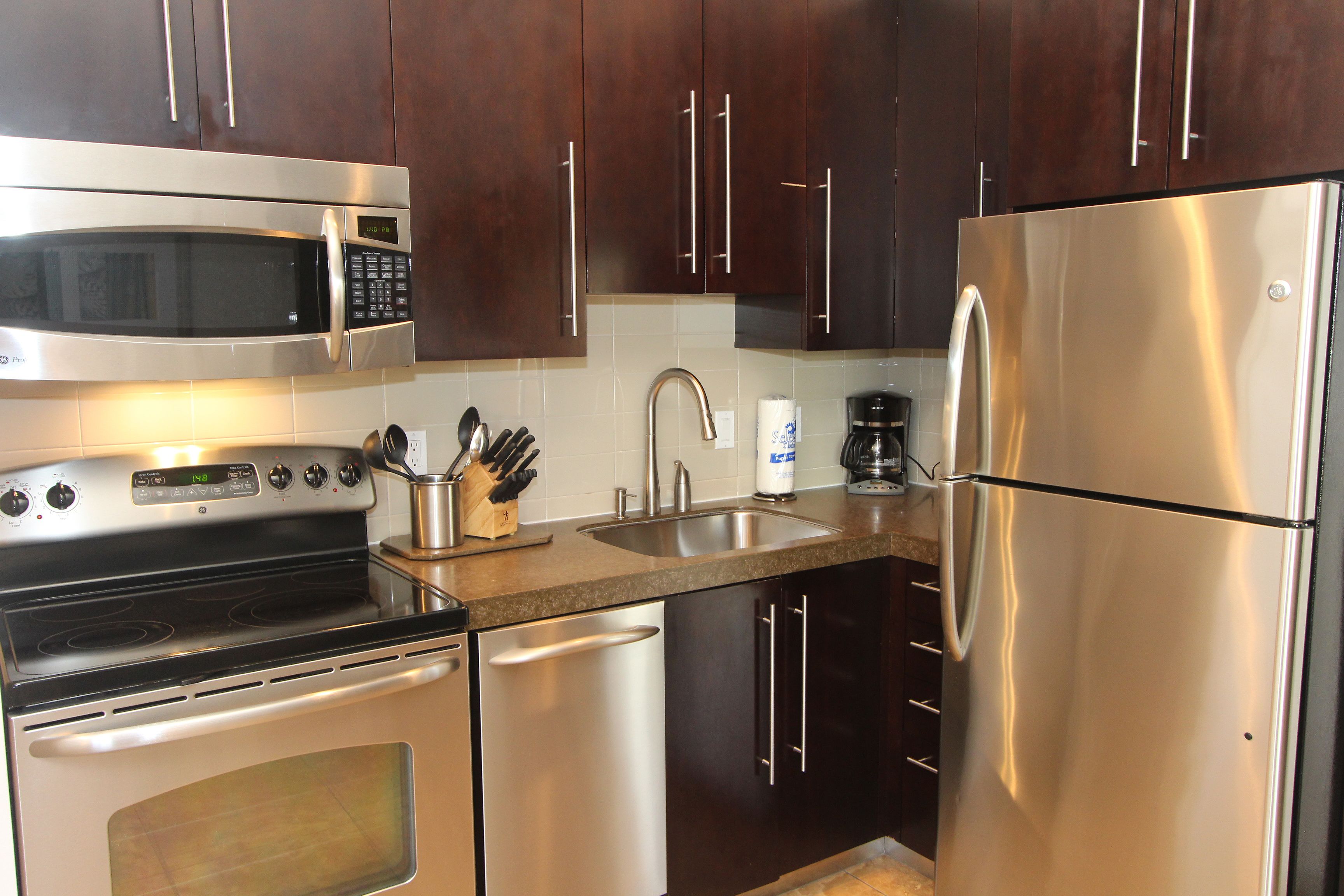 A modern kitchen with stainless steel appliances, including a microwave, oven, and refrigerator.
