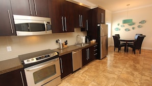 A modern kitchen with dark wood cabinets, stainless steel appliances, and a tiled floor.