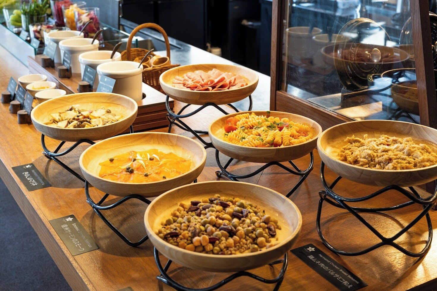 A buffet with various dishes displayed in wooden bowls on stands.