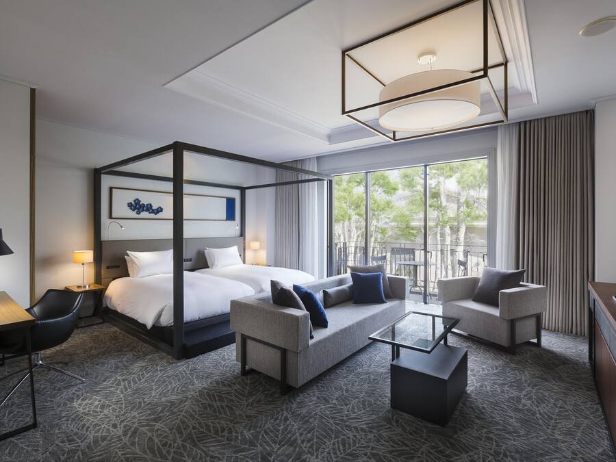 A hotel room with a four-poster bed, a sofa, a coffee table, and a TV.