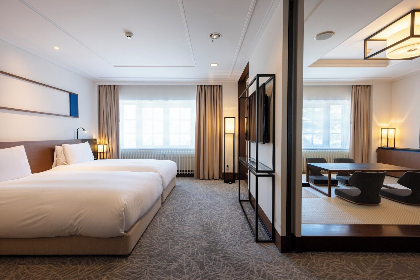 Habitación de hotel con dos camas, un escritorio y vistas a la ciudad.