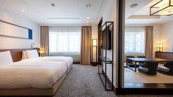 Habitación de hotel con dos camas, un escritorio y vistas a la ciudad.