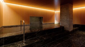 Un vestíbulo moderno con piso de mármol pulido, paneles de madera y un pilar de piedra.