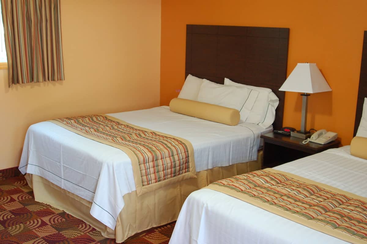 Une chambre d’hôtel avec deux lits, une table de chevet avec une lampe et un téléphone.