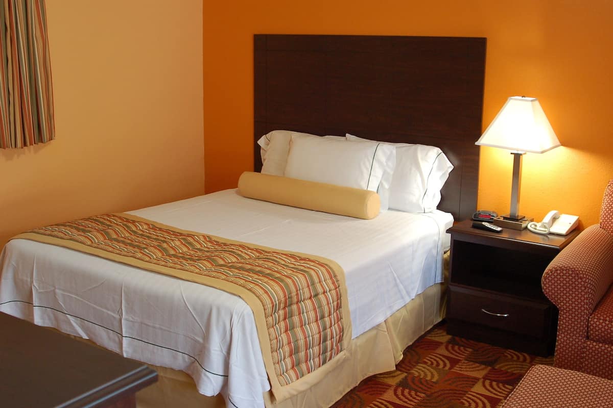 Une chambre d’hôtel avec un lit, une table de chevet avec une lampe et un téléphone.