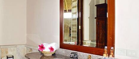 Un baño con encimera de mármol, un lavabo blanco, un mueble de madera y un espejo sobre el lavabo.
