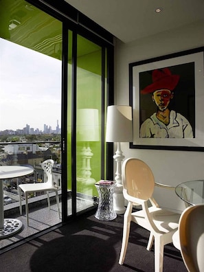 Enjoy a city view from the balcony, featuring a large window, a comfortable chair, and a floor lamp.