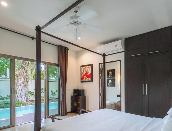 A bedroom with a bed, a ceiling fan, a large window, and a view of a swimming pool. - Two Villas Holiday Oriental Style Naiharn Beach (Rawai)