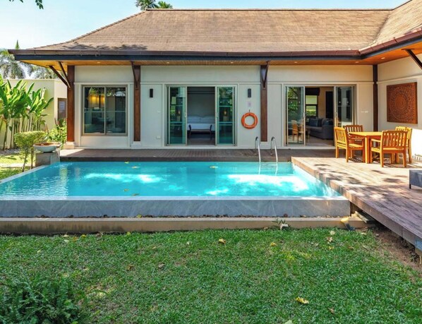 Una casa moderna con piscina, un porche cubierto y un dormitorio con cama.