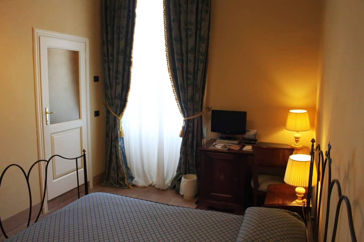 A hotel room with a bed, a television, a lamp, and curtains.