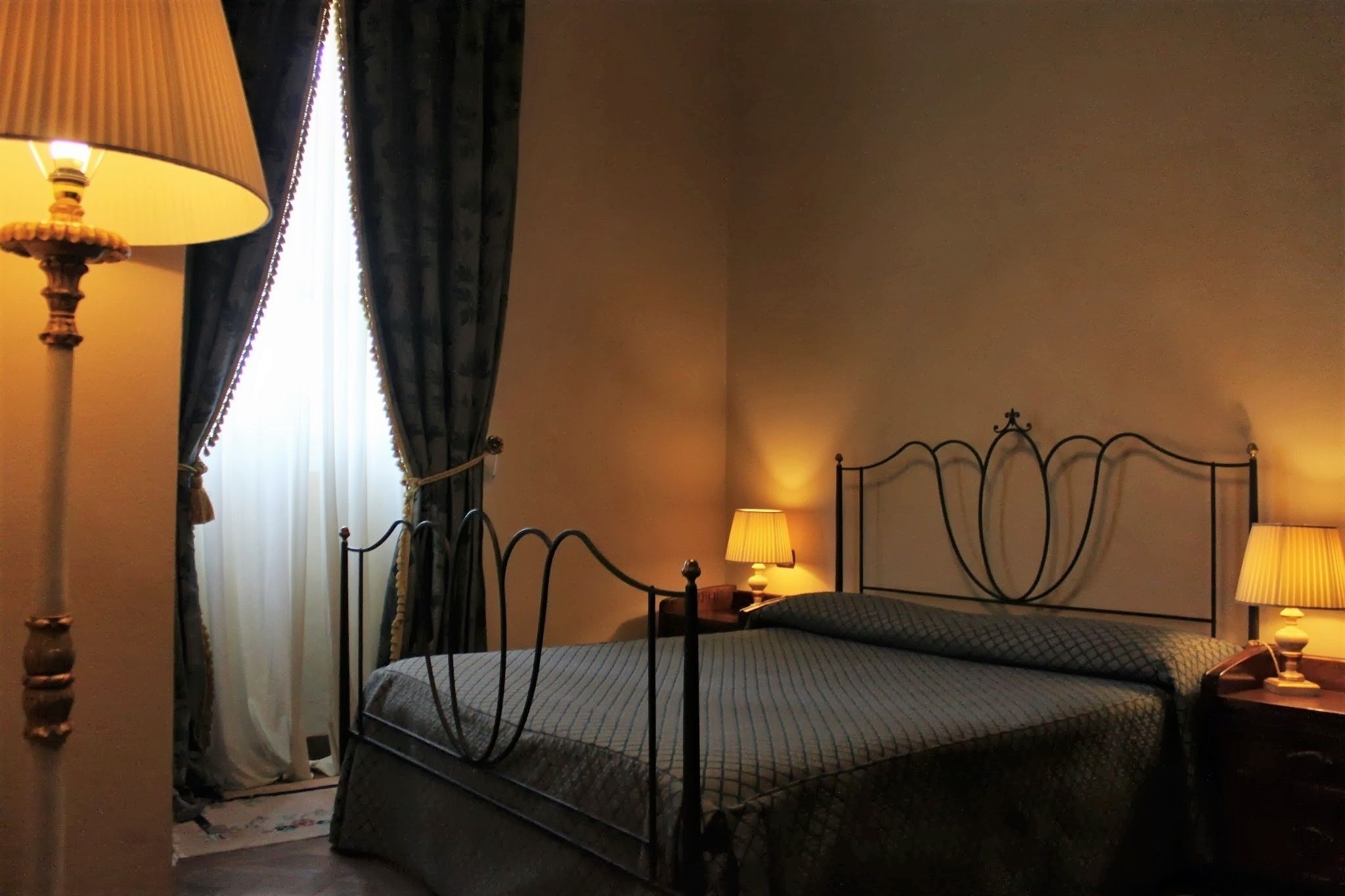 Une chambre à coucher avec un lit, deux lampes de chevet, une fenêtre avec des rideaux et une table de chevet.
